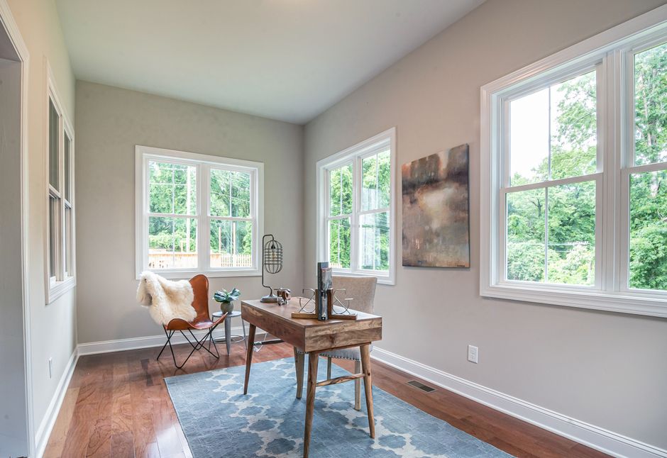 A sunny home office featuring modern furniture, decor, and abundant natural light from large windows.