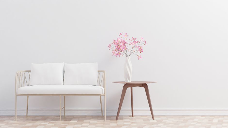 Elegant minimalist living room featuring a cozy sofa and table with floral decor.